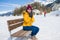 Unique Winter holidays trip to amazing snow valley - young happy and beautiful Asian woman sitting on bench alone enjoying snowy