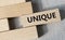UNIQUE - word on a wooden bar on a gray background