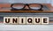 UNIQUE - word on wooden cubes on the background of a folder with documents and glasses