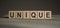 Unique word written on wooden blocks on gray