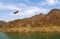 United Arab Emirates flag waving on top of a hill in the Middle of Hatta lake on blue fluffy cloudy sky background