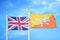 United Kingdom and Bhutan two flags on flagpoles and blue cloudy sky