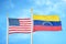 United States and Venezuela two flags on flagpoles and blue cloudy sky