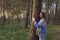 Unity with nature: young calm girl hugging pine tree trunk with closed eyes walking in autumn forest