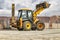 The universal backhoe loader lifted up the bucket on the construction site. Rental of construction equipment for earthworks.