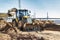 A universal excavator is working on a construction site against a cloudy sky. Earthworks at a construction site. Modern