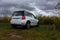 Universal white crossover car parked for travelers on the territories of coastal reserves in the Pskov region, west of the Izborsk