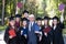 University professor and seven graduates rejoice at graduation.