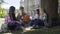 University students gathered under tree, having discussion, working on project