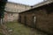 Unkempt Courtyard of an Old Prison Full of Weeds and Cells