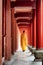Unknown Buddhist monk walking along red wooden corridor