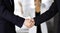 Unknown businesspeople are shaking their hands after signing a contract, while standing together in a modern office