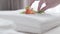 Unknown Caucasian maid putting tender flower on crystal clear white towels lying on bed. Unrecognizable woman making bed