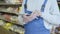 Unknown Caucasian man in uniform standing in grocery and using tablet. Unrecognizable man swiping screen checking