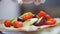 Unknown chef adds cherry tomatoes to cooked vegetables, in the frame of the chef`s hand