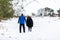 An unknown couple taking a walk through a snowy countryside landscape