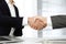 Unknown diverse business people are shaking hands finishing up meeting at the desk in office, close-up. Handshake