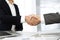 Unknown diverse business people are shaking hands finishing up meeting at the desk in office, close-up. Handshake