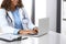 Unknown doctor woman typing on laptop computer while sitting at the desk in hospital office. close-up of hands