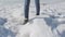 Unknown female in jeans and trekking winter shoes walking in deep snow