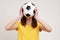 Unknown female with wavy hair football fan in casual style yellow t-shirt supporting her favorite team covering face with soccer