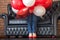 Unknown girl hidden in red and white helium balloons on sofa. Colorful balloons and women legs in red shoes. Birthday decoration.