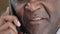 Unknown half face part old wrinkled emotional businessman African mature man talking on mobile phone unrecognizable boss