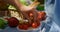 Unknown human hands take tomatoes on picnic closeup. Man arm hold red vegetables