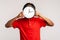 Unknown man with dreadlocks wearing red casual style T-shirt, hiding face behind big wall clock