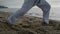 Unknown man legs making karate kicks on sand close up. Athlete stepping on beach