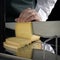 Unknown person cuts cheese using a cheese slicer