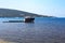 Unknown semi-submerged rusted and destroyed barge stranded in a bay