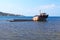 Unknown semi-submerged rusted and destroyed barge stranded in a bay