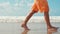 Unknown teenager walking at beach. Boy legs leaving footprints at coastline.
