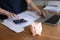 Unknown woman counts expenses, closeup focus piggybank on table