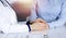 Unknown woman-doctor is holding her patient`s hands to reassure a patient, while sitting together at the desk in the