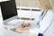 Unknown woman-doctor at work filling up medication history record form in clinic, close-up of clipboard