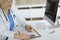 Unknown woman-doctor at work filling up medication history record form in clinic, close-up of clipboard