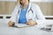 Unknown woman-doctor at work filling up medication history record form in clinic, close-up of clipboard