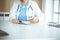 Unknown woman-doctor at work filling up medication history record form in clinic, close-up of clipboard