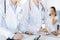 Unknown woman-doctors at work with patient at the background. Female physicians filling up medical documents or