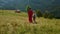 Unknown woman walking daughter on green hill. Mother and child enjoying vacation