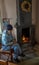 Unknown woman warms herself at indoor fireplace