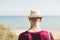 Unknown young man in hat and with bag goes to the sea beach