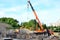 Unloading of cargo and building materials by mobile truck crane at the construction site.