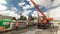 Unloading concrete plates from truck by crane at road construction site timelapse.