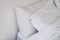 Unmade bed close-up with white bedsheet and pillows.