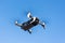 Unmanned drone flies through the air against the blue sky.