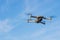 An unmanned quadcopter with a digital camera in the blue sky.