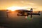 Unmanned quadcopter in flight with a digital camera at sunset. Drone silhouette at sunset